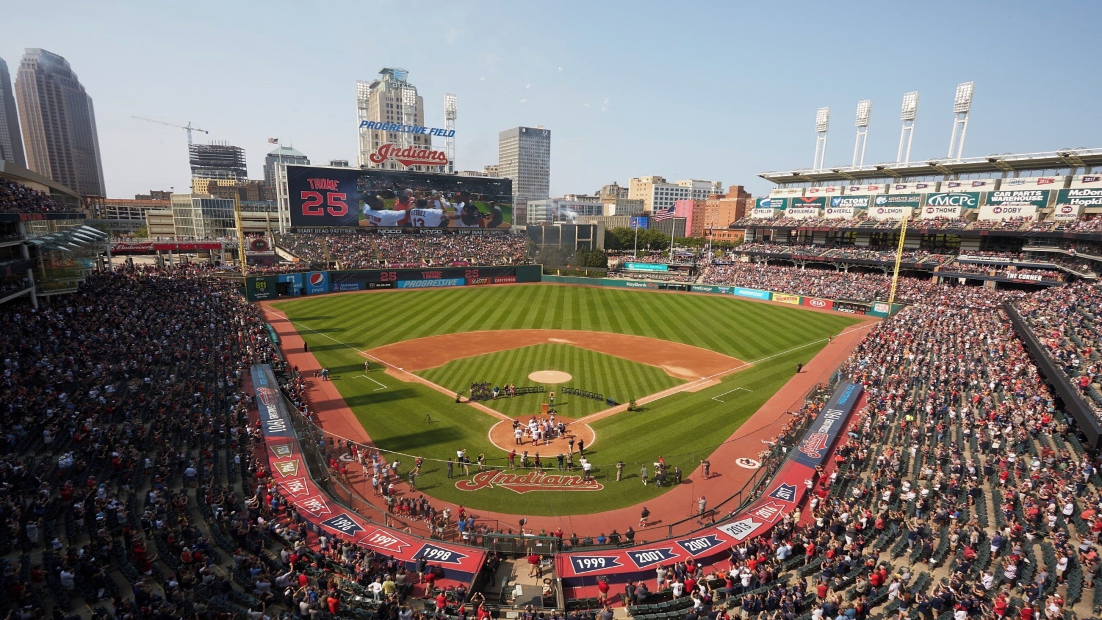 A baseball stadium with multiple tiers of seating, a large scoreboard, and advertisements.