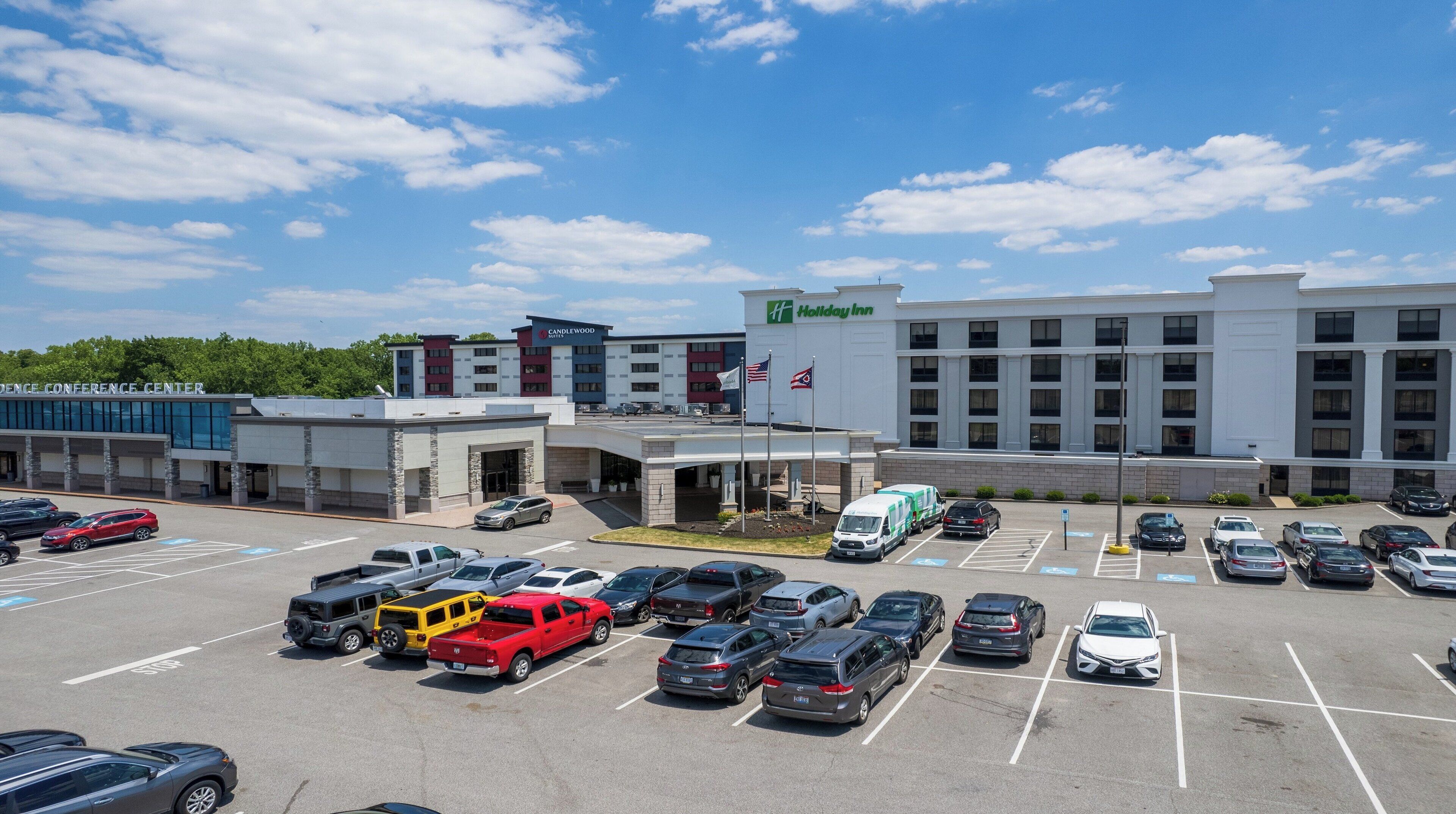 Un Holiday Inn Express con un estacionamiento lleno de coches y un edificio de varios pisos con una bandera.