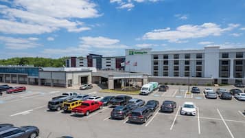 Un Holiday Inn Express con un estacionamiento lleno de coches y un edificio de varios pisos con una bandera.
