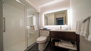 A modern bathroom with a glass shower enclosure, a toilet, a sink with a mirror, and a towel rack. - Holiday Inn Cleveland-S Independence by IHG (Independence)