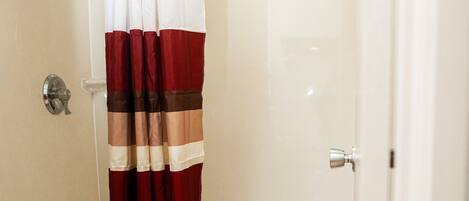 A bathroom with a shower curtain, a toilet, and a bathtub.