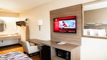 Una camera d'albergo con un letto, una scrivania, una televisione a parete, un forno a microonde e un piccolo frigorifero.