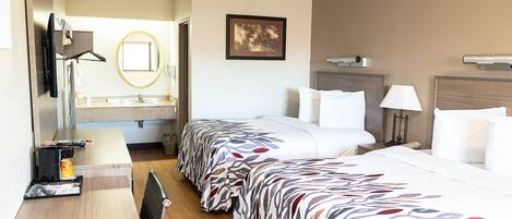 Una habitación de hotel con cama, mesita de noche, lámpara y un cuadro en la pared.