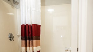 A bathroom with a shower curtain, a toilet, and a bathtub. - Red Roof Inn Rochester - Henrietta (Henrietta)