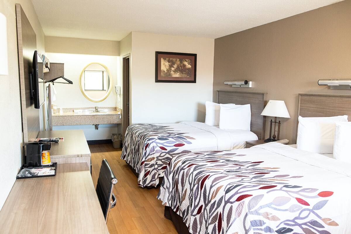 A hotel room with a bed, bedside table, lamp, and a framed picture on the wall.