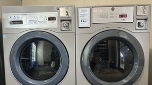 Two front-loading washing machines with digital displays, control panels, and a small window on the front. - Red Roof Inn Rochester - Henrietta (Henrietta)