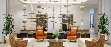 A modern lobby with wicker chairs, a central coffee table, and hanging decor.