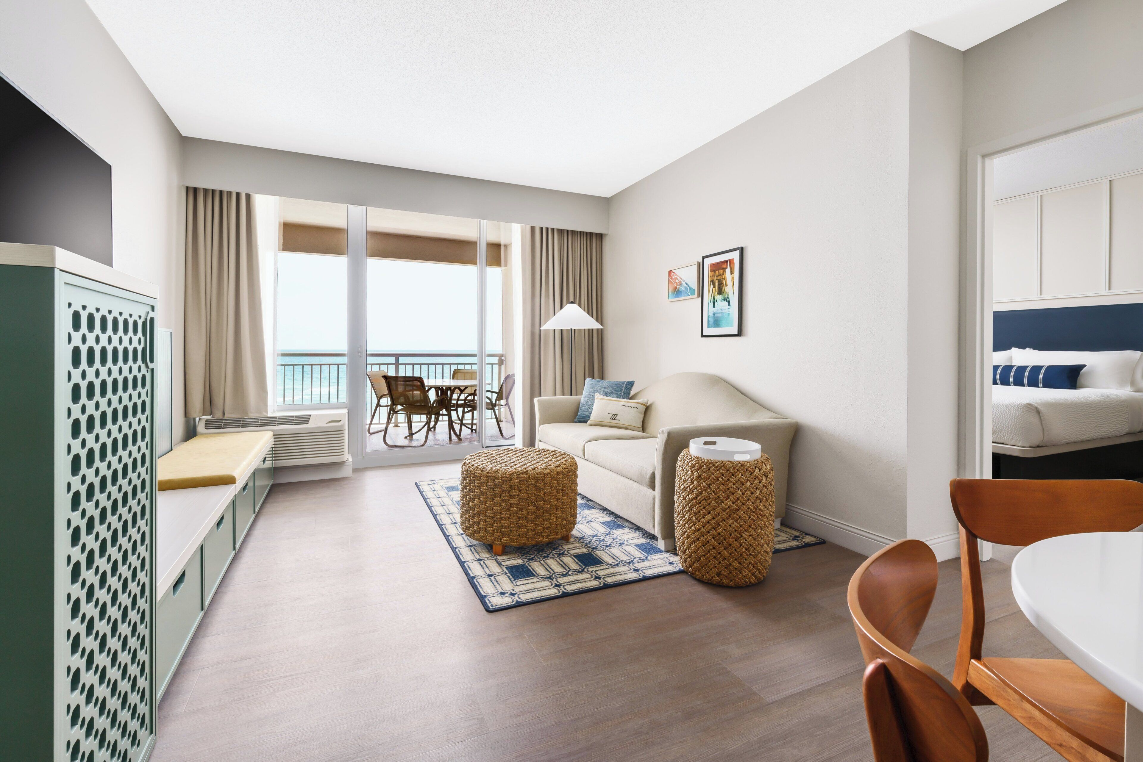 Et moderne hotelværelse med balkon, sofa, spisebord og tekøkken.