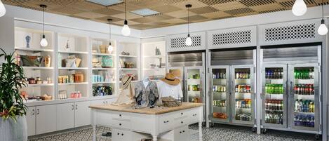 Una cocina moderna con armarios blancos, una isla central, lámparas colgantes y suelo estampado.