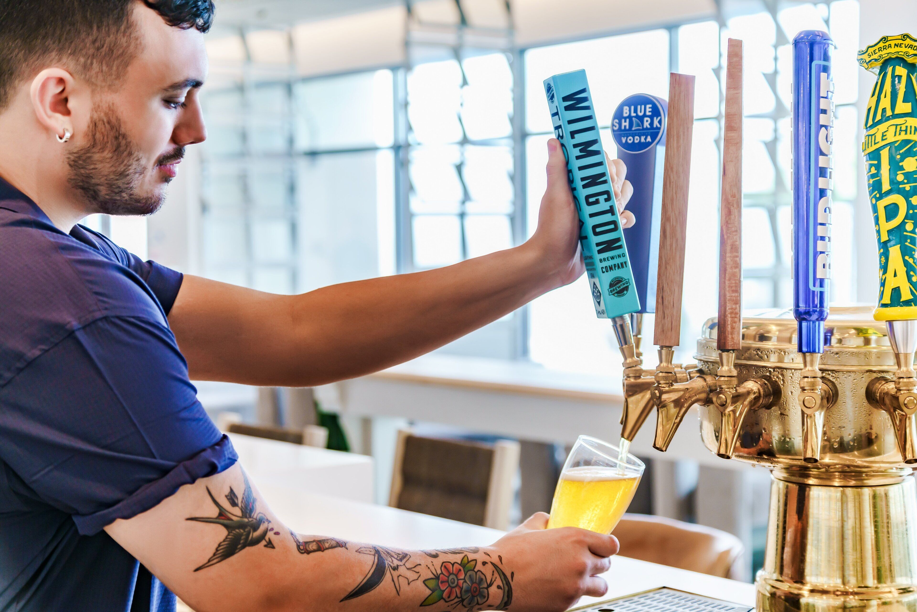 Uma pessoa servindo cerveja de uma torneira com a etiqueta 'Wilmington'.