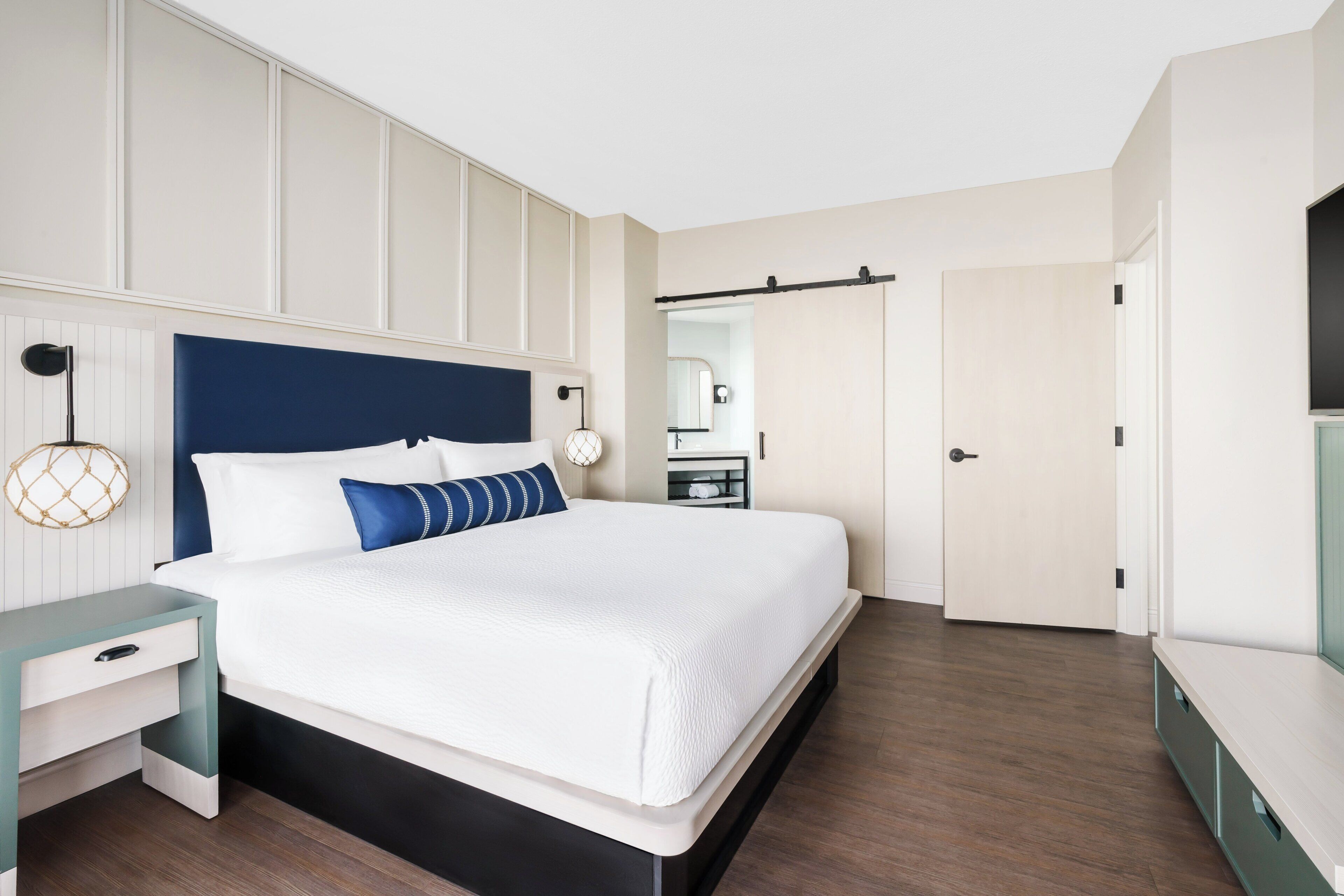 Quarto moderno com cama, mesa de cabeceira e guarda-roupa.