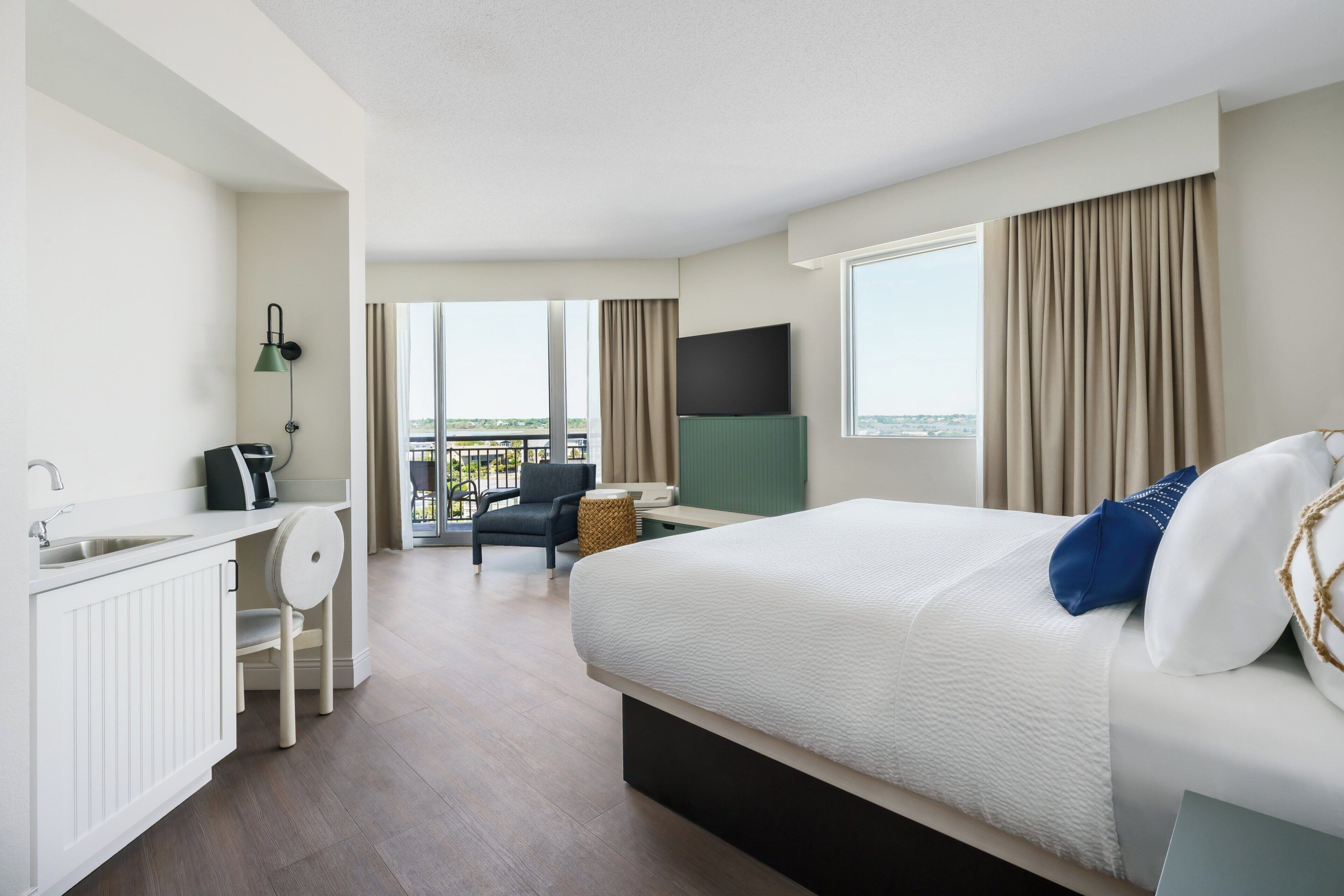 Ein Hotelzimmer mit Bett, Schreibtisch mit Stuhl, Fernseher und Blick ins Freie.