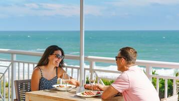 Una pareja cenando en una mesa con vista al océano.