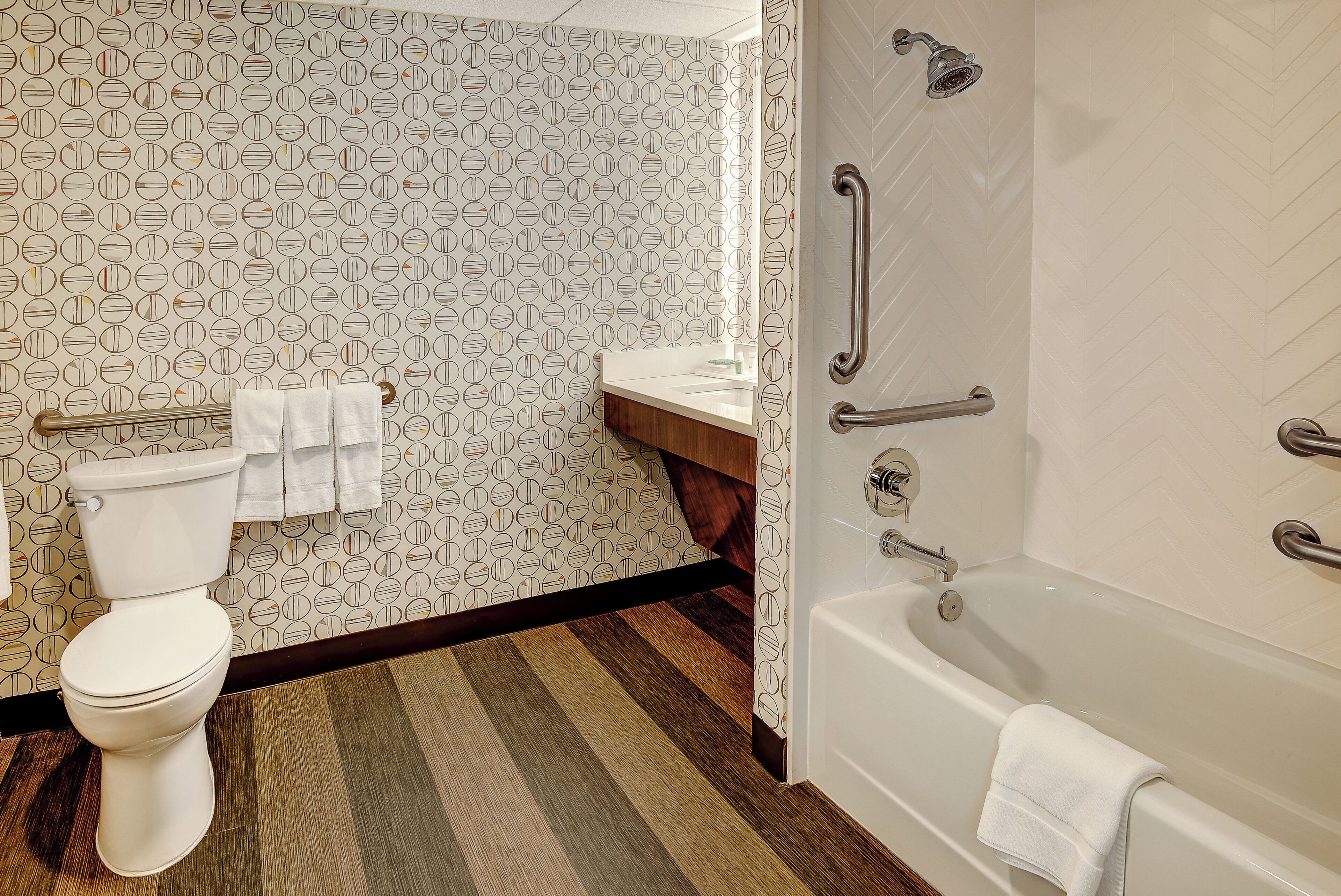 A bathroom with a toilet, a sink, and a bathtub. There are towels hanging on a rack.