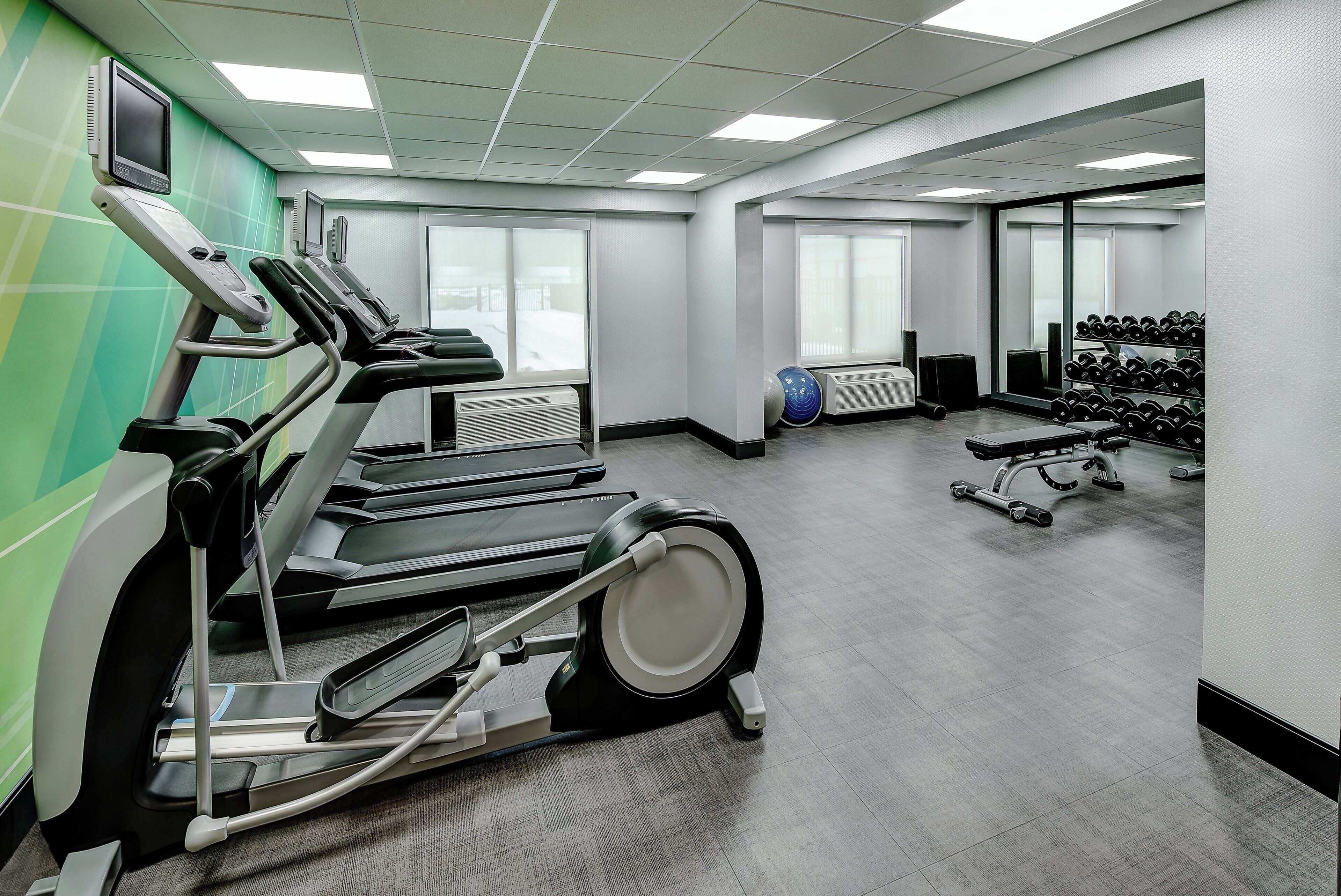 Une salle de sport équipée de tapis de course, d’un vélo d’appartement et d’un porte-haltères.
