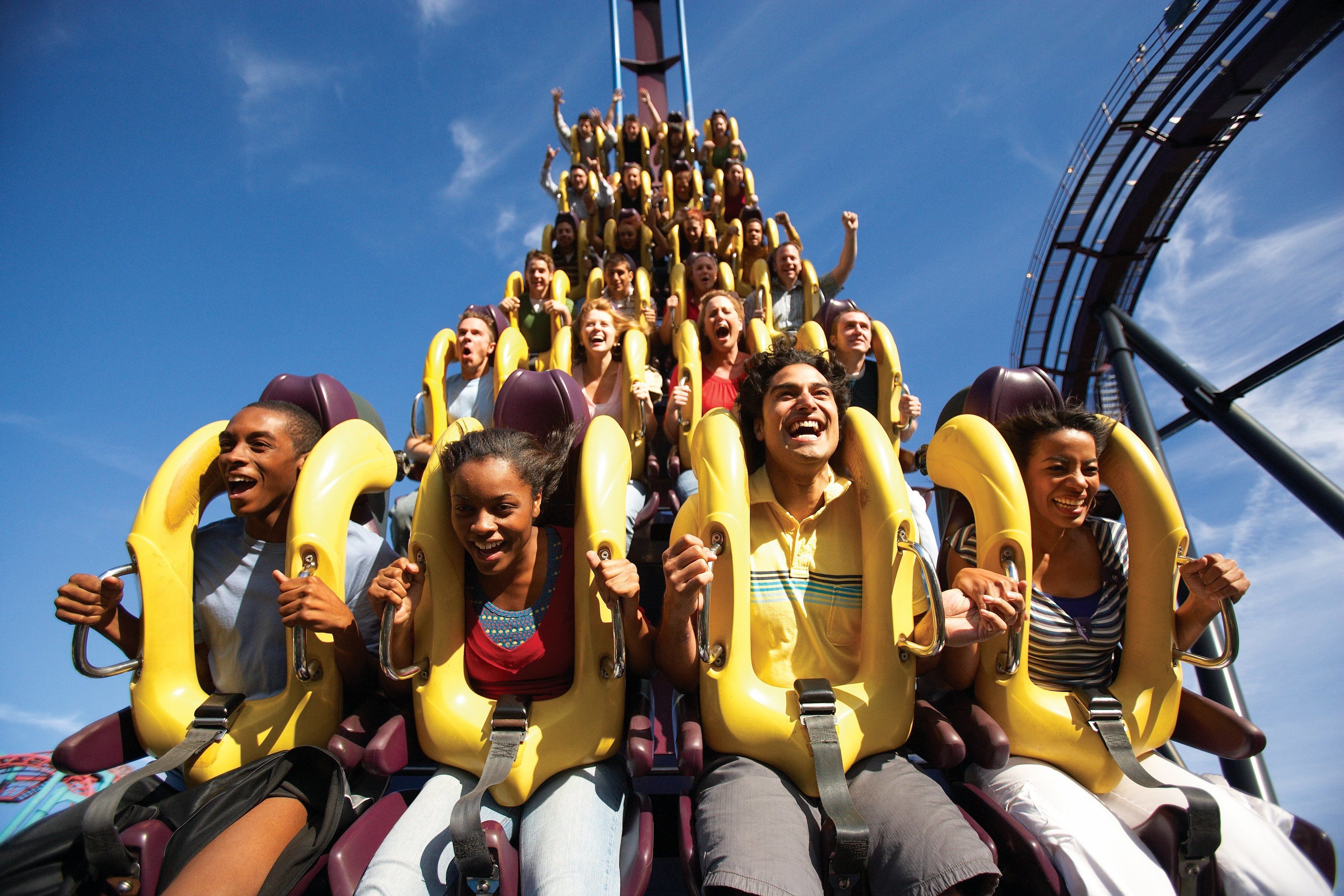 A group of people on a roller coaster with yellow seats and safety harnesses.