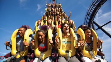 A group of people on a roller coaster with yellow seats and safety harnesses.