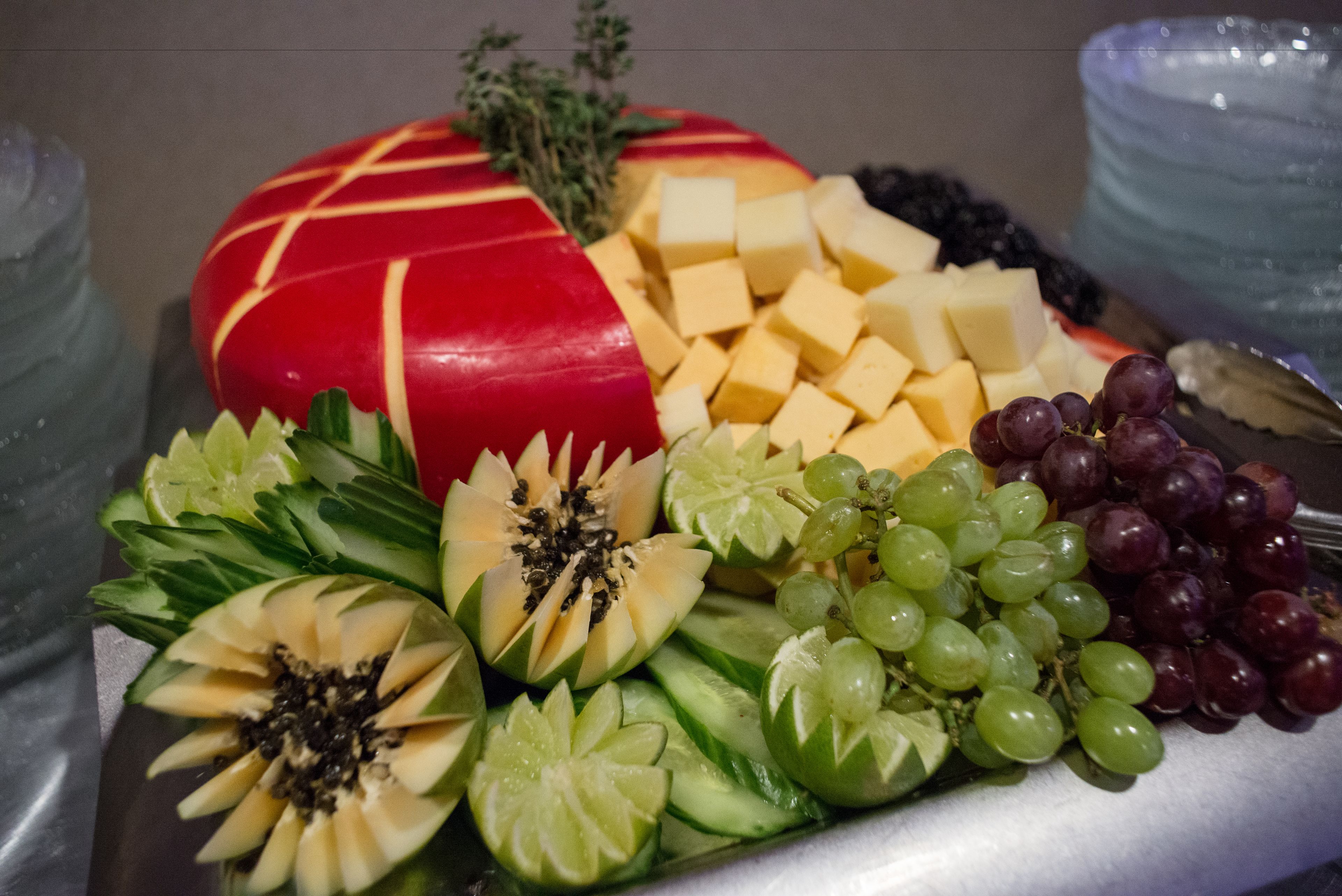 Una bandeja con queso, uvas y frutas cortadas.