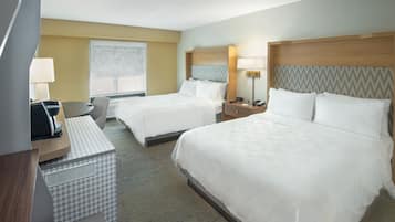 A hotel room with two beds, a desk, a chair, and a window with a view.