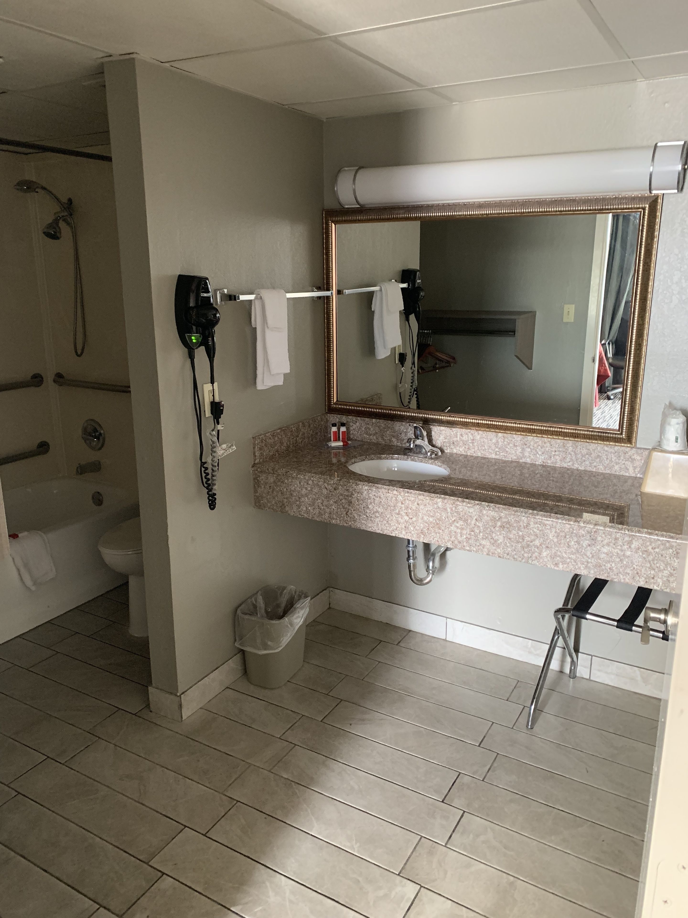 Un bagno moderno con lavandino, specchio, portasciuga e zona doccia.