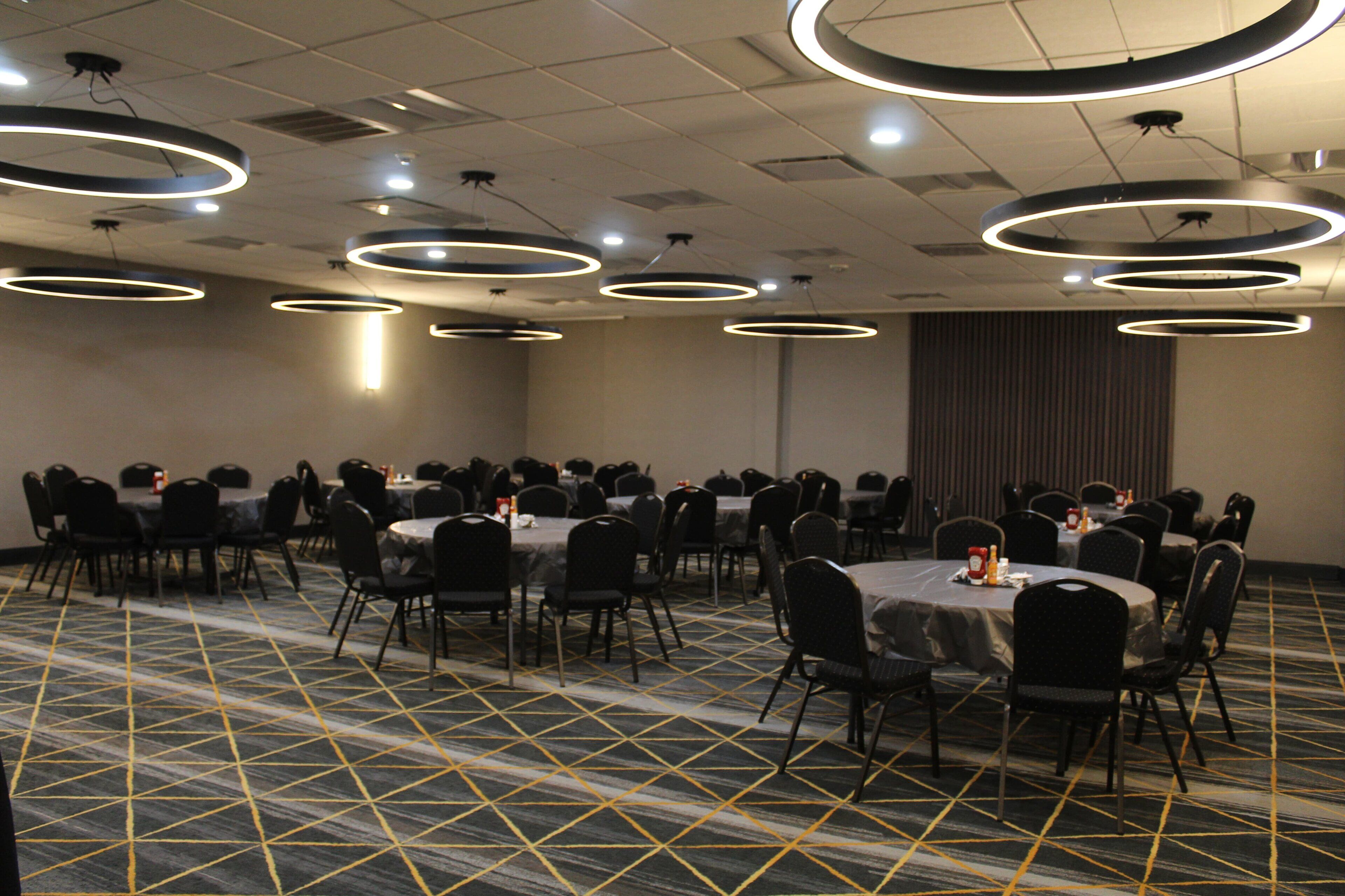 Un salón de conferencias con varias mesas y sillas, dispuestas en filas.
