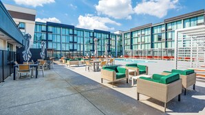 A rooftop pool area with outdoor seating and a modern building in the background.