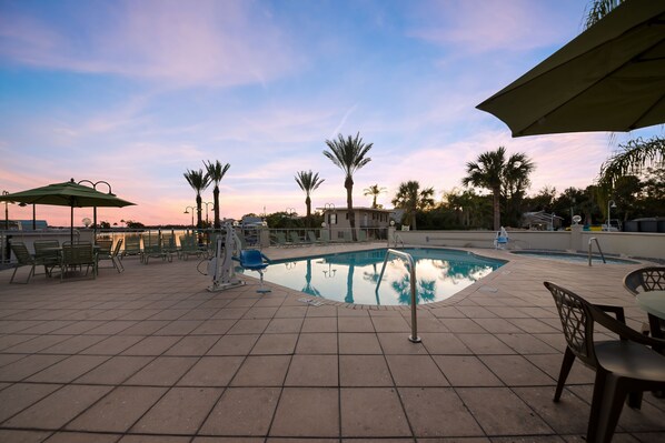 Una piscina al aire libre, sombrillas, sillones reclinables de piscina