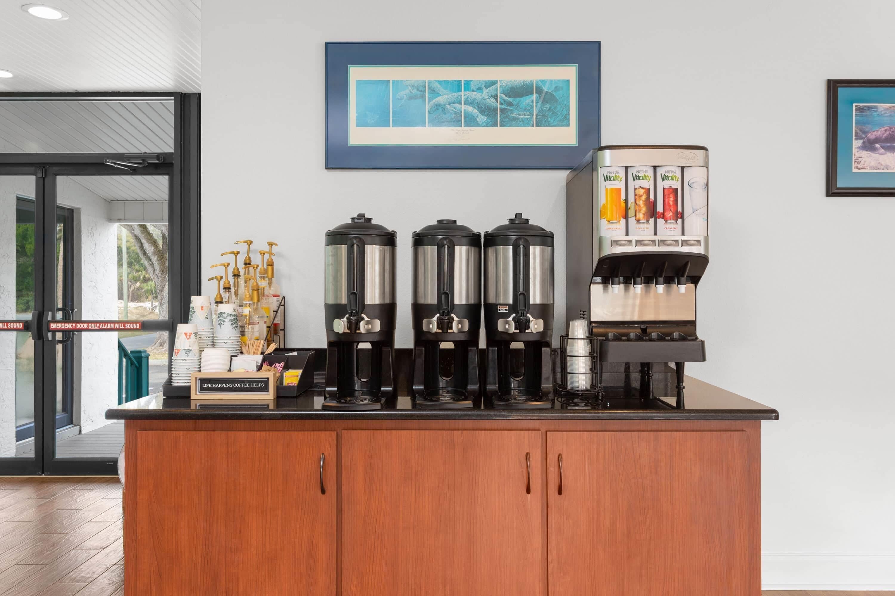 A coffee station with multiple coffee makers and a beverage dispenser.