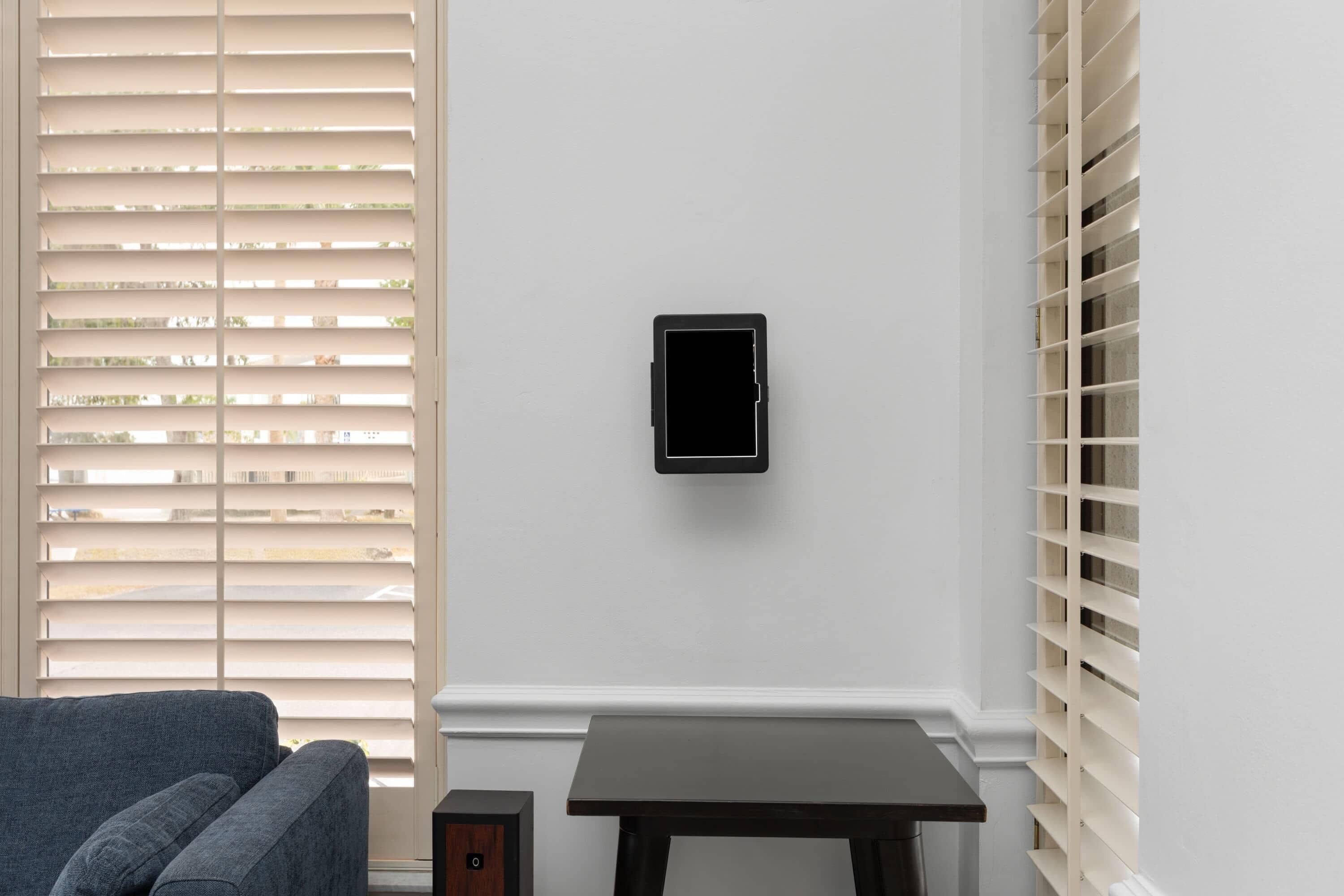A room with a grey sofa, a small table, and a wall-mounted device.