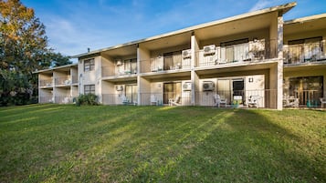 Un immeuble à plusieurs étages doté de balcons, de climatiseurs et d’espaces de détente en plein air.