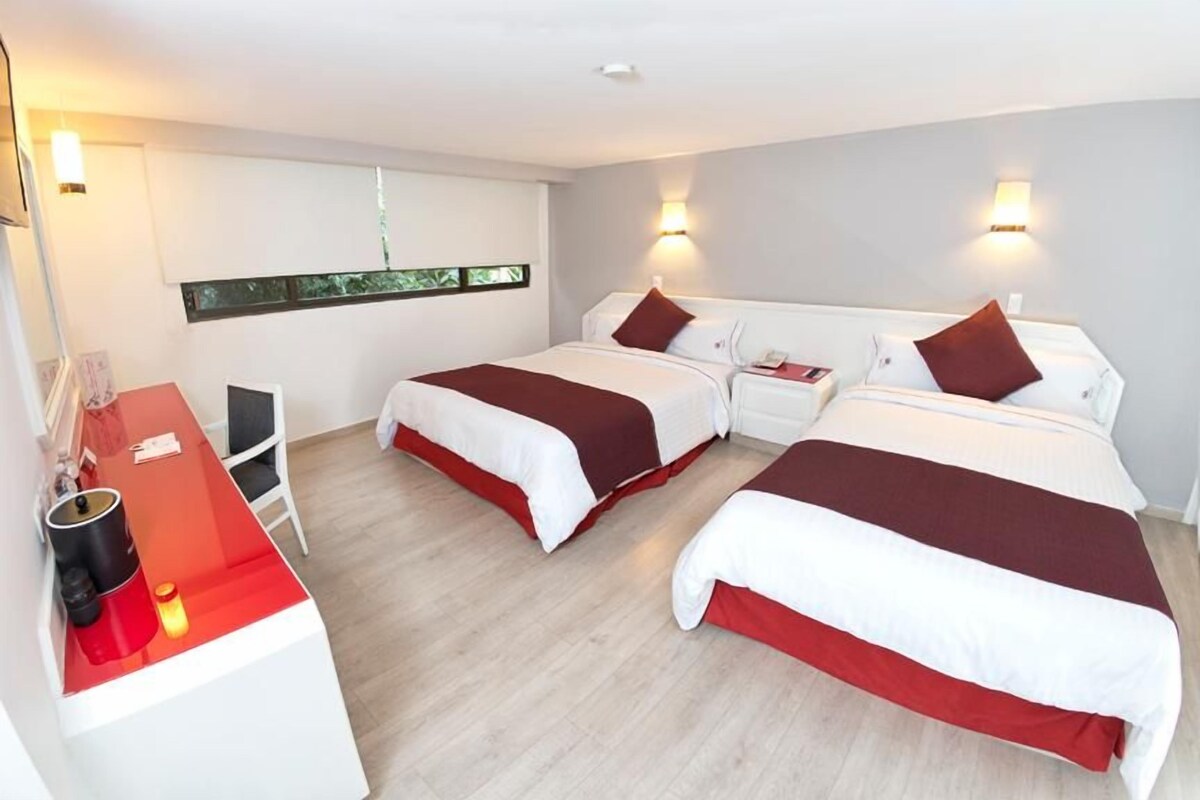 A hotel room with three beds, a desk, and a chair.