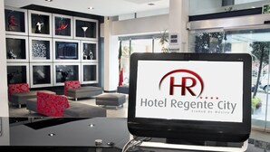 A modern hotel lobby with a digital display of the Hotel Regency City logo. - Regente Hotel (Mexico City)