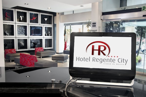 Un moderno vestíbulo de hotel con una pantalla digital que muestra el logotipo del Hotel Regency City.