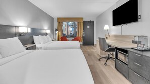 Una habitación de hotel moderna con dos camas, un escritorio con cafetera, televisor y vista a la ciudad.