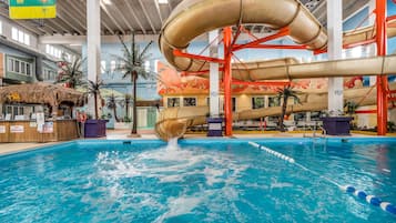 An indoor water park with a large pool, slides, and tropical decor.