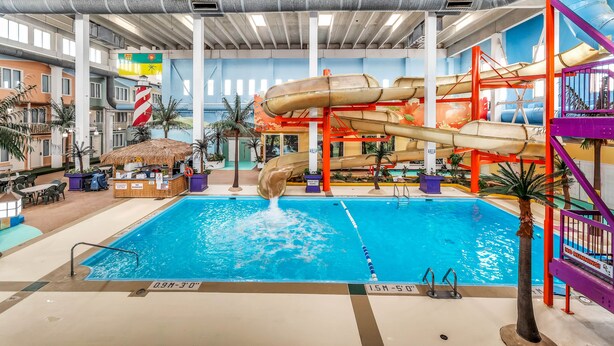 Una piscina interior con toboganes, una zona de bar y un área de descanso junto a la piscina.