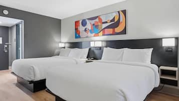 A modern hotel room with two beds, a large abstract painting, and a minimalist design.