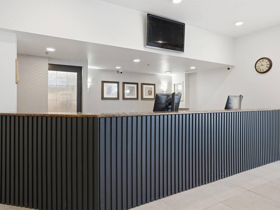 A reception desk with a flat-screen TV, framed pictures, and a clock on the wall.