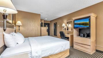 Habitación de hotel con cama, escritorio, televisor y vistas a un lago.