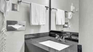 A bathroom with a sink, two towels hanging on a rack, and a hairdryer mounted on the wall.