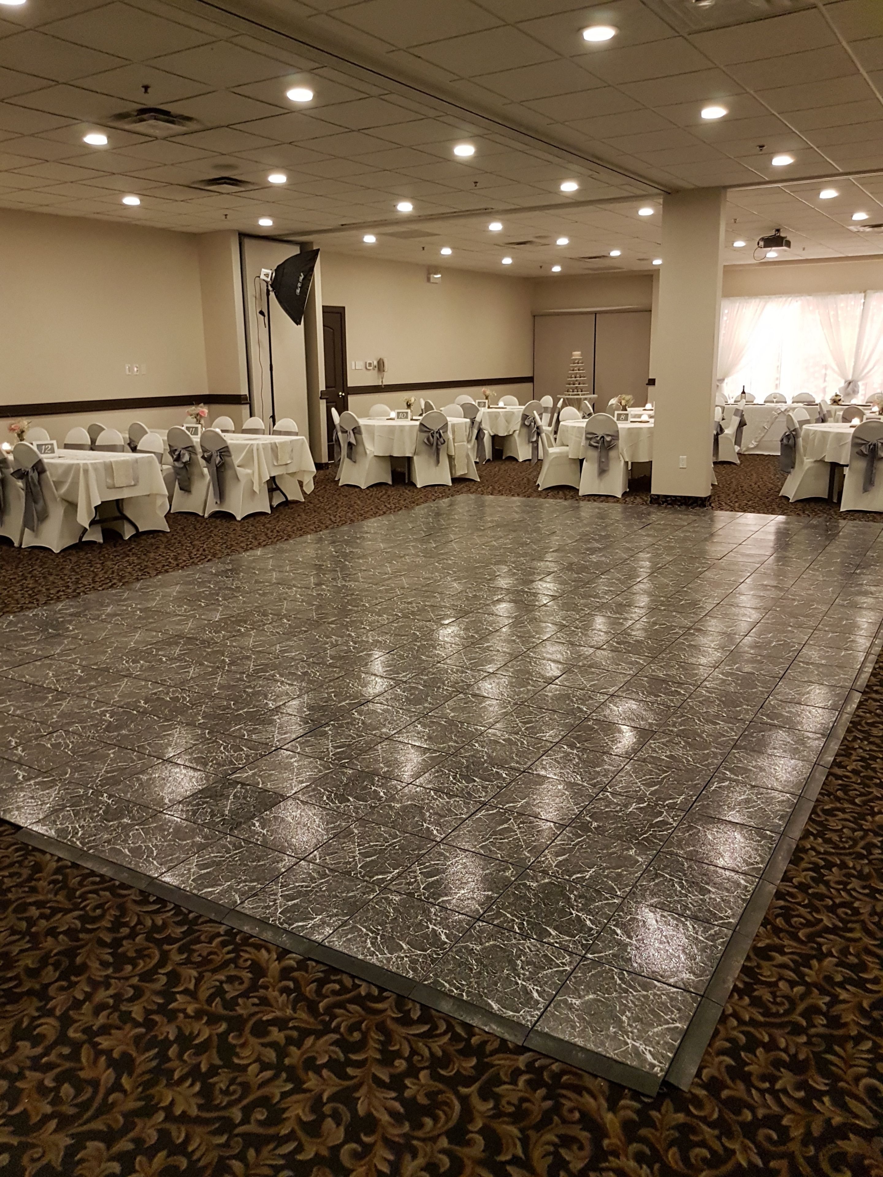 A large conference room with a polished marble floor, white tables with grey sashes, and a patterned carpet.