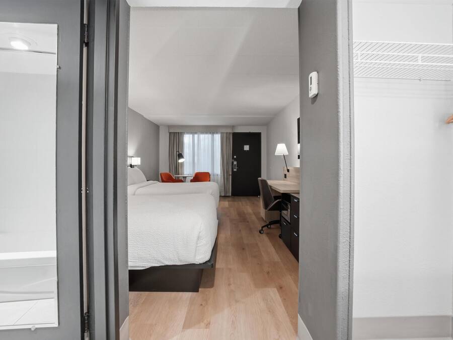 A hotel room with a bed, desk, chair, and a wardrobe.