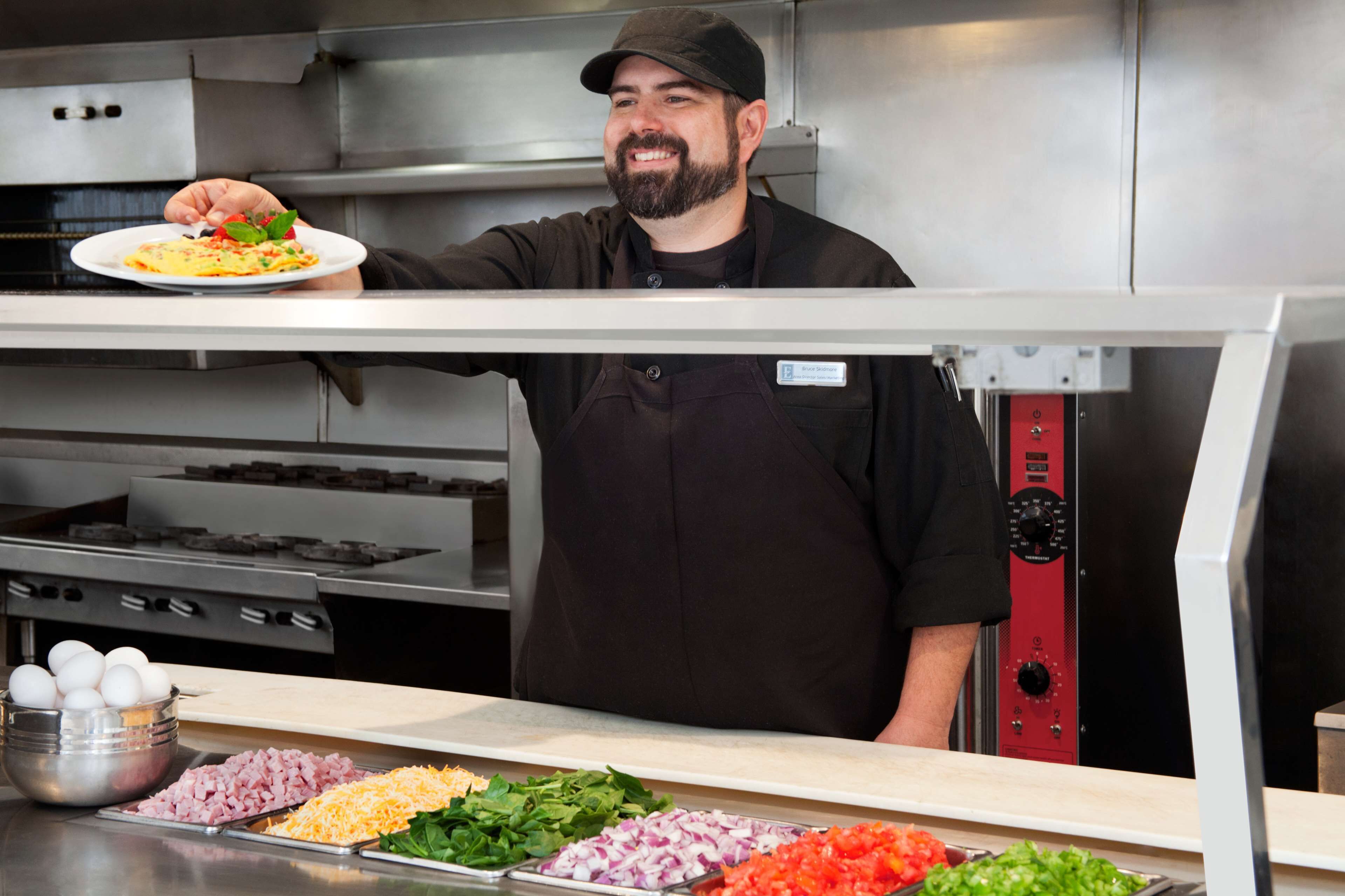 A chef in a kitchen holding a plate of food.