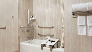Een moderne badkamer met een badkuip, handgrepen en een handdoekhouder.