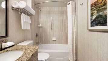 Un baño con bañera, inodoro, lavabo y ducha con puerta de cristal.