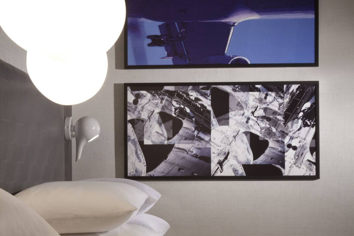 Un dormitorio moderno con una cama, una mesita de noche y dos cuadros en la pared.