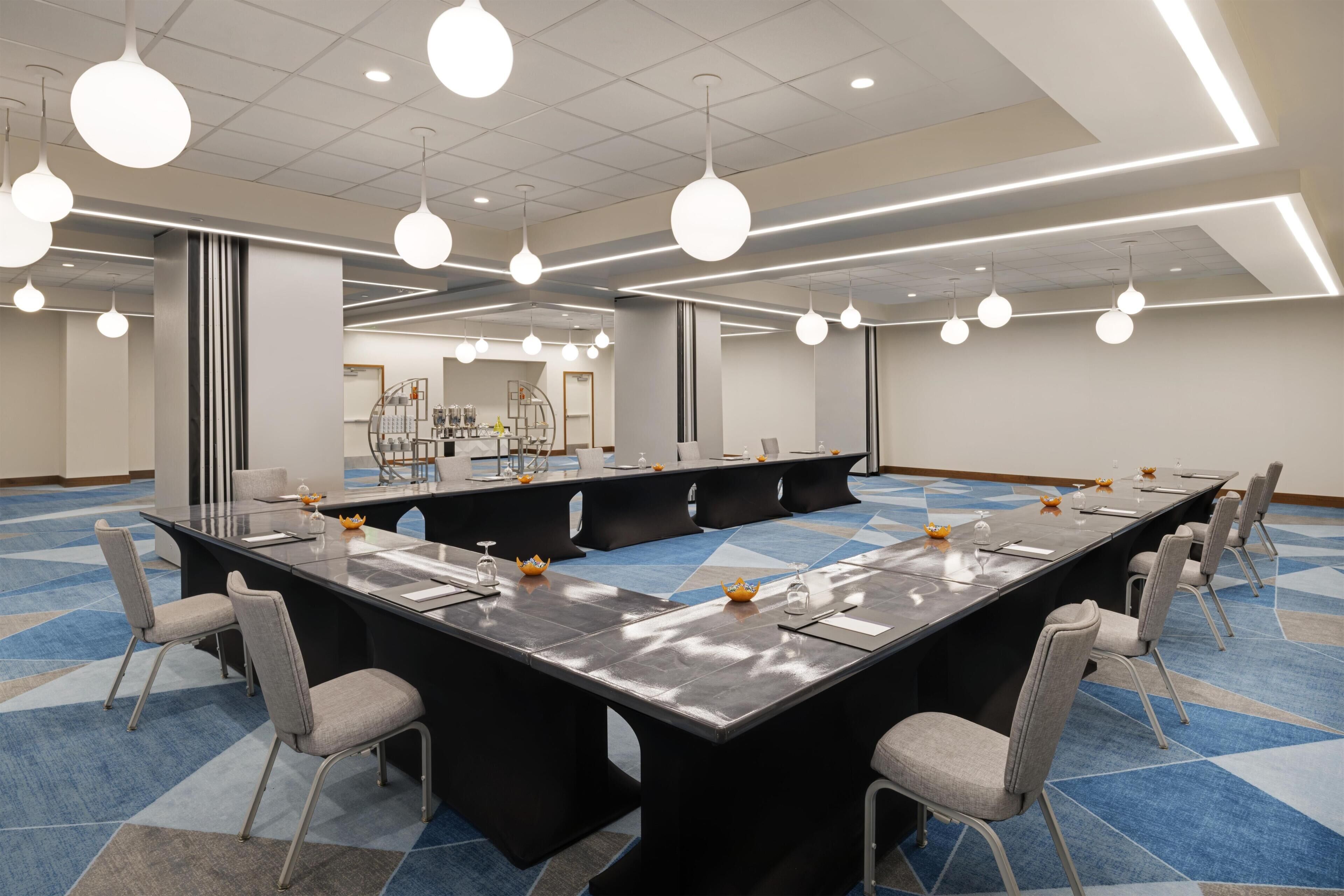 A conference room with a long table, multiple chairs, and pendant lighting.