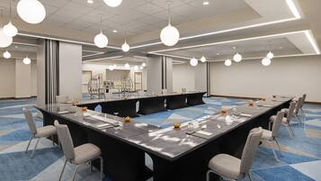 A conference room with a long table, multiple chairs, and pendant lighting.