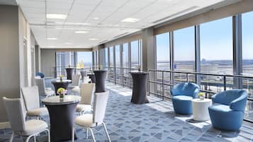Um lobby de hotel moderno com teto alto, janelas amplas e piso com padrão geométrico.