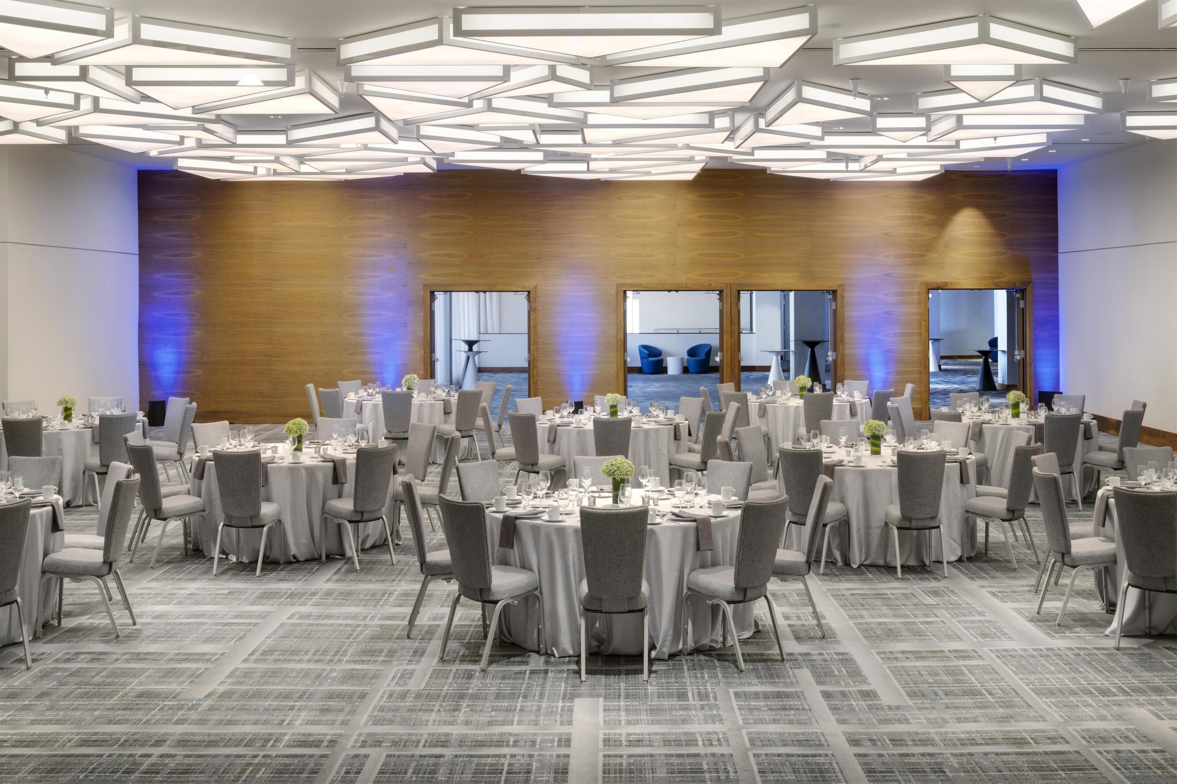 A large conference room with round tables, grey chairs, and a modern ceiling design.